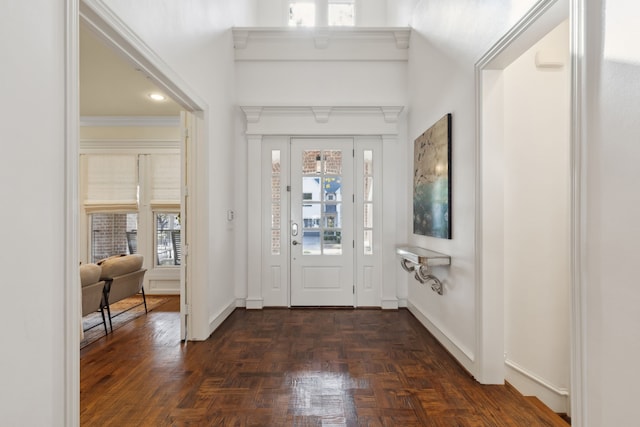 foyer with dark parquet flooring and ornamental molding