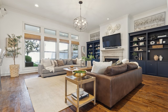 living room featuring built in shelves, ornamental molding, dark wood-type flooring, and an inviting chandelier