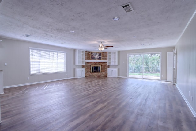 unfurnished living room featuring ceiling fan, dark hardwood / wood-style floors, a fireplace, and a textured ceiling