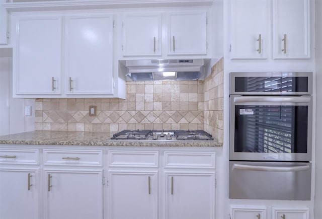 kitchen with light stone countertops, white cabinetry, appliances with stainless steel finishes, and backsplash