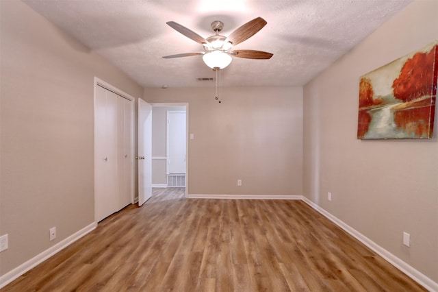 spare room featuring ceiling fan, wood-type flooring, and a textured ceiling