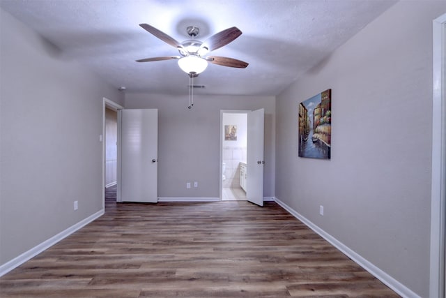 unfurnished bedroom with wood-type flooring, ceiling fan, and ensuite bathroom