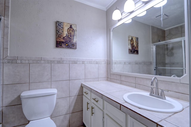 bathroom with toilet, a shower with shower door, tile walls, ornamental molding, and vanity