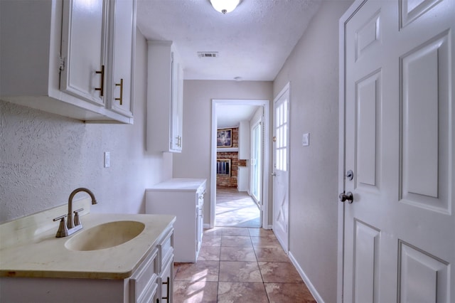 bathroom with a fireplace, sink, and a textured ceiling