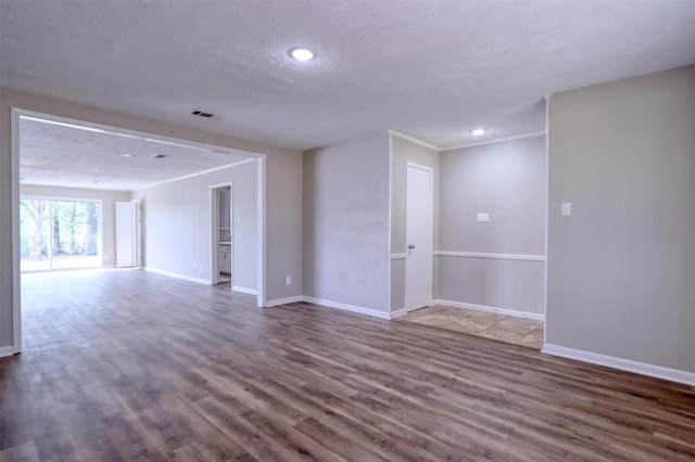 empty room with hardwood / wood-style flooring, ornamental molding, and a textured ceiling