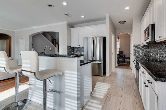 kitchen featuring decorative backsplash, stainless steel appliances, white cabinetry, and dark stone counters