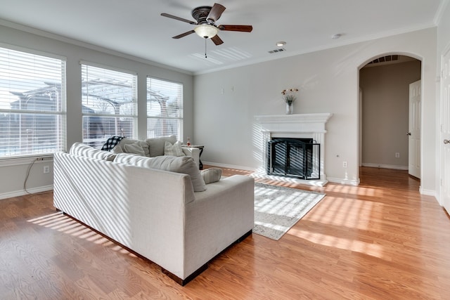 living room featuring wood-type flooring, ceiling fan, and crown molding