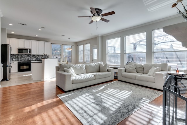 living room with light wood-type flooring, plenty of natural light, and ceiling fan