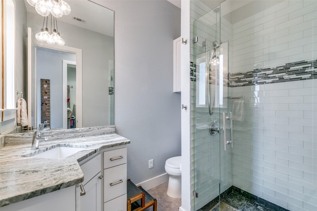 bathroom featuring vanity, toilet, a shower with shower door, and an inviting chandelier