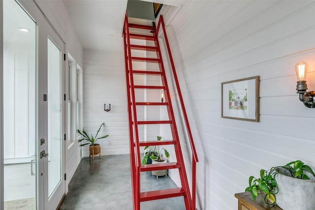 stairway with wood walls and concrete flooring