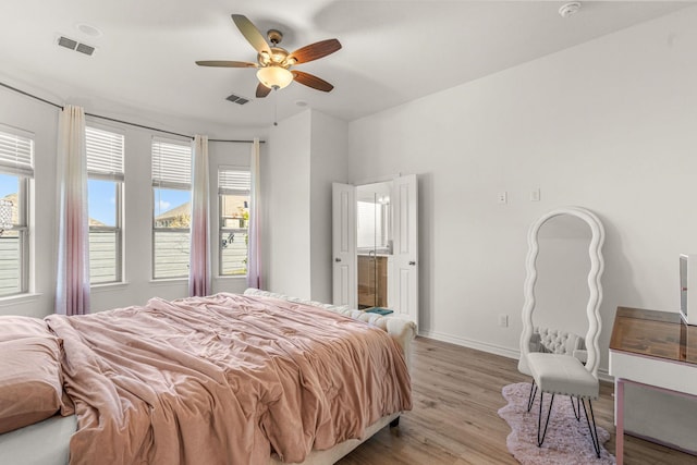 bedroom featuring multiple windows, ceiling fan, connected bathroom, and light wood-type flooring