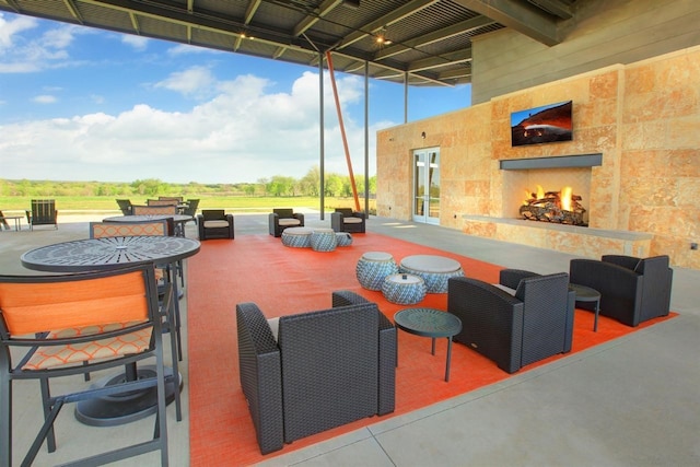 view of patio with an outdoor living space with a fireplace and french doors