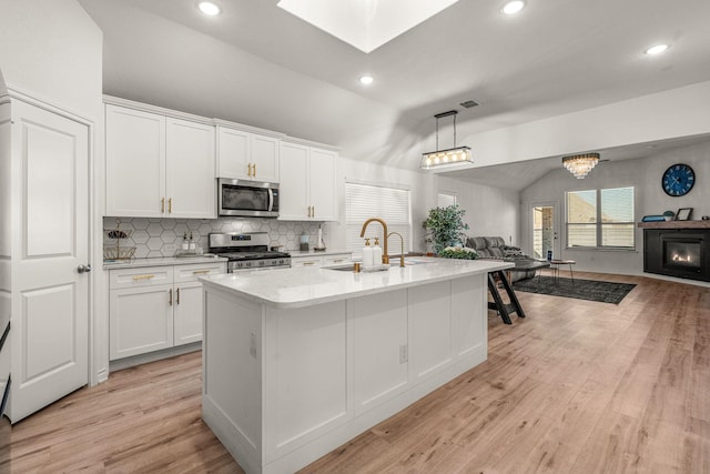 kitchen featuring white cabinets, an island with sink, vaulted ceiling, and appliances with stainless steel finishes