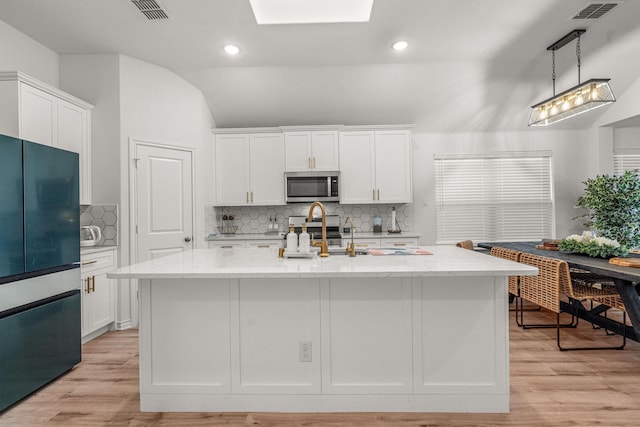 kitchen with light stone counters, an island with sink, white cabinets, and appliances with stainless steel finishes