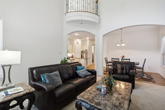 carpeted living room featuring a towering ceiling and a chandelier