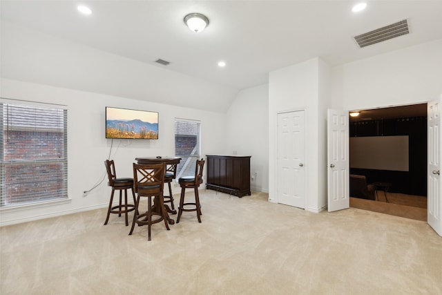 dining room with vaulted ceiling and light colored carpet