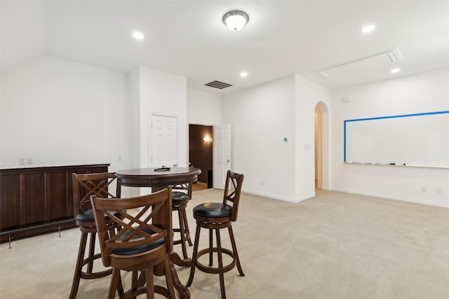 dining space featuring lofted ceiling and light colored carpet