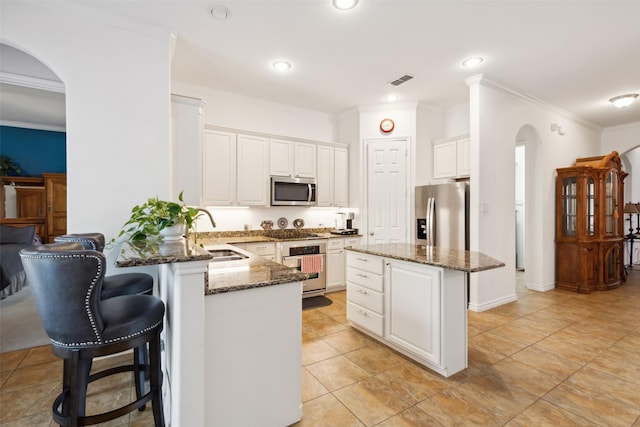 kitchen featuring sink, a center island, dark stone counters, stainless steel appliances, and white cabinets