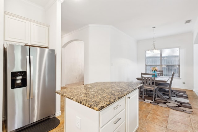 kitchen featuring stainless steel refrigerator with ice dispenser, white cabinetry, crown molding, a center island, and dark stone countertops