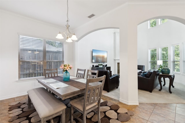 dining room featuring crown molding, a towering ceiling, a chandelier, and light tile patterned floors