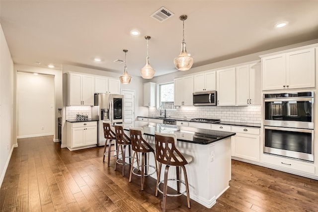 kitchen featuring hanging light fixtures, stainless steel appliances, a center island, and white cabinets