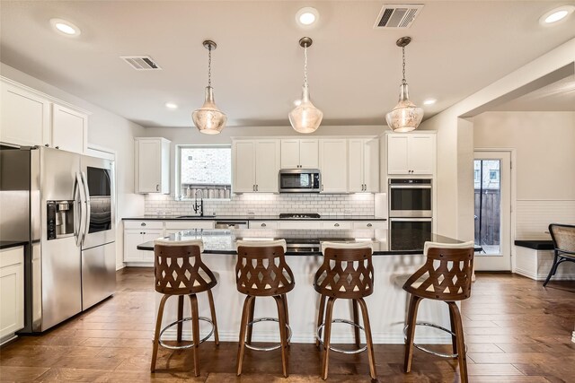 kitchen featuring decorative light fixtures, a center island, a kitchen breakfast bar, and appliances with stainless steel finishes