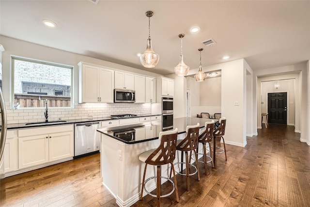 kitchen featuring sink, a center island, decorative light fixtures, white cabinets, and appliances with stainless steel finishes