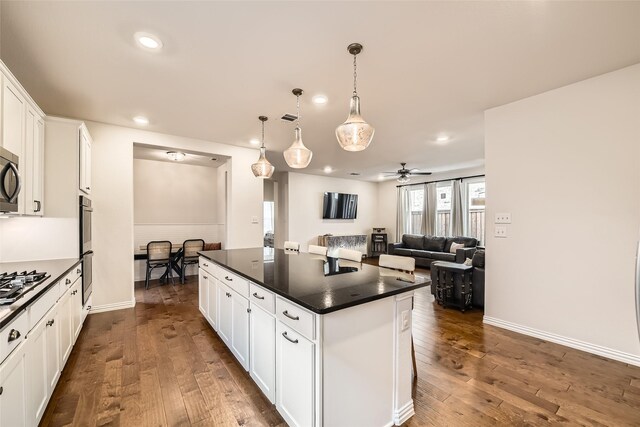 kitchen featuring white cabinets, ceiling fan, a kitchen island, and pendant lighting