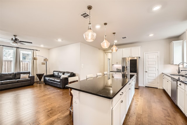 kitchen featuring a center island, hanging light fixtures, a kitchen bar, white cabinetry, and stainless steel appliances