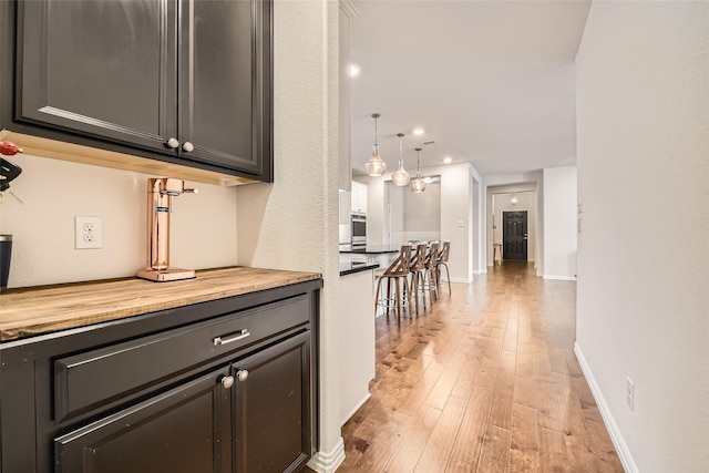 interior space featuring wood counters, stainless steel oven, light wood-type flooring, and hanging light fixtures