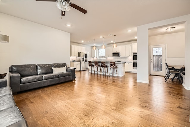 living room featuring light hardwood / wood-style floors and ceiling fan