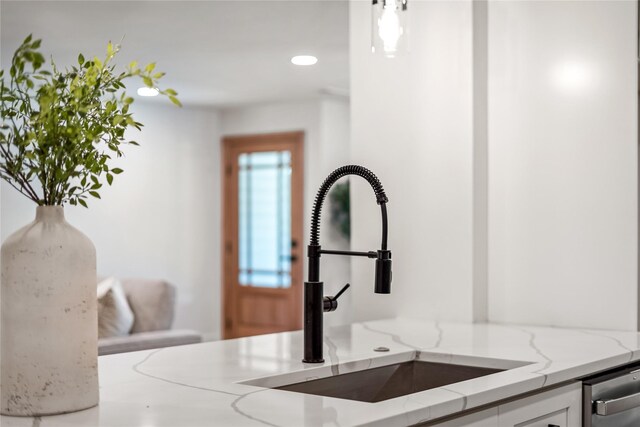 details featuring white cabinetry, sink, and light stone countertops