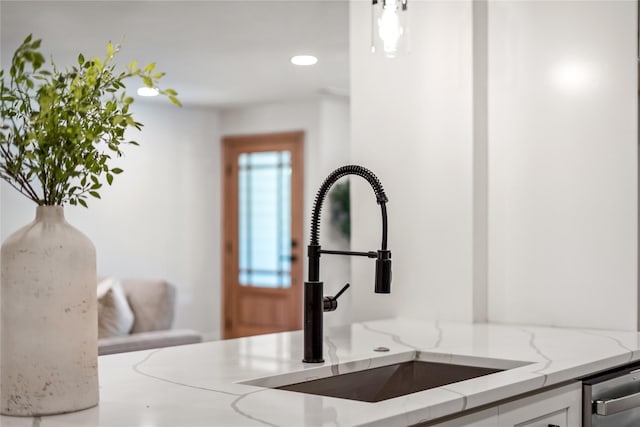 room details featuring white cabinetry, sink, and light stone counters