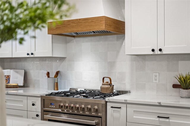 kitchen featuring white cabinets, decorative backsplash, light stone countertops, stainless steel range, and custom range hood