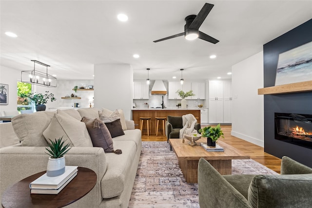 living room featuring ceiling fan with notable chandelier and light hardwood / wood-style floors