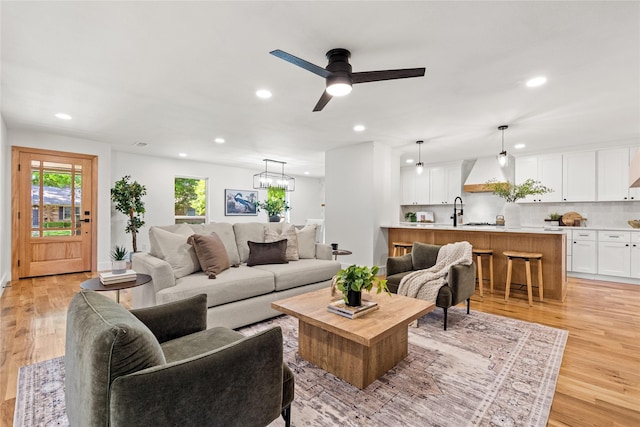 living room with sink, light hardwood / wood-style flooring, and ceiling fan