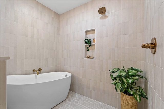 bathroom featuring tile patterned flooring, a bath, and tile walls