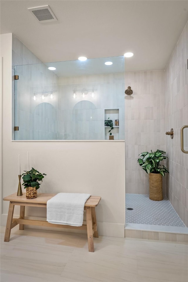 bathroom with a tile shower, tile patterned floors, and tile walls