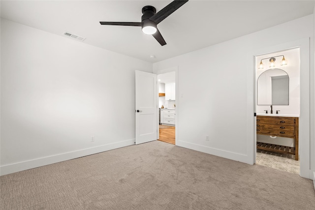 unfurnished bedroom featuring ceiling fan, light colored carpet, and connected bathroom