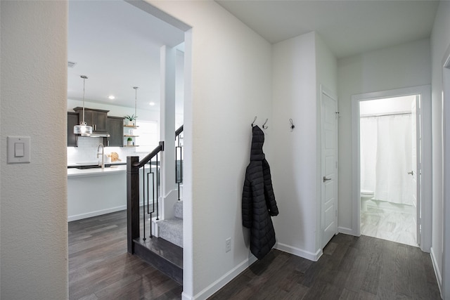 corridor with dark hardwood / wood-style flooring and sink