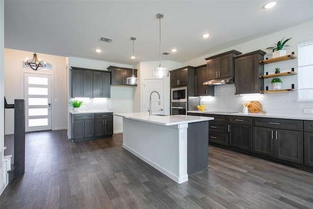 kitchen featuring pendant lighting, a center island with sink, sink, dark hardwood / wood-style floors, and built in microwave