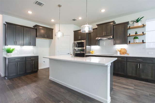 kitchen featuring decorative light fixtures, a center island with sink, dark hardwood / wood-style floors, and black electric stovetop