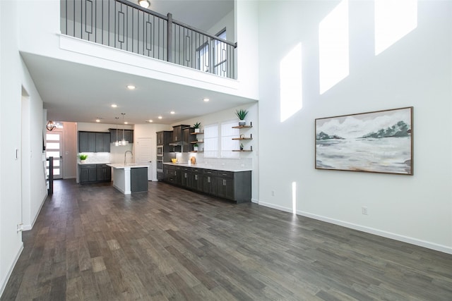 unfurnished living room with dark hardwood / wood-style floors, a towering ceiling, and sink