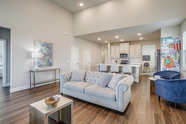 living room with a high ceiling and dark hardwood / wood-style flooring