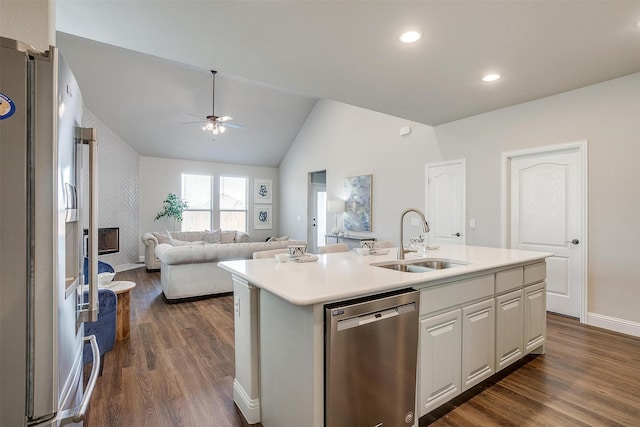 kitchen with sink, a large fireplace, an island with sink, stainless steel appliances, and white cabinets