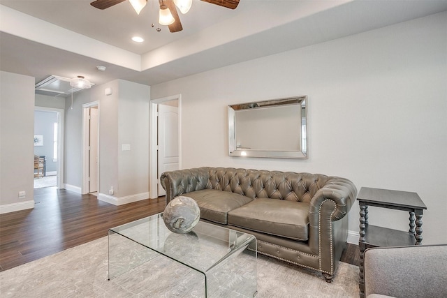 living room with a tray ceiling, wood-type flooring, and ceiling fan