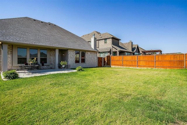 back of house with a patio and a lawn