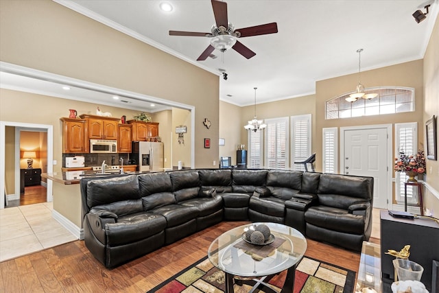 living room with ceiling fan with notable chandelier, light wood-type flooring, and ornamental molding