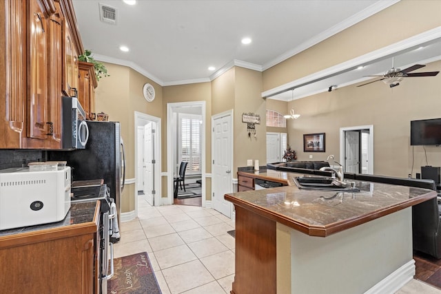 kitchen with ceiling fan, sink, an island with sink, light tile patterned flooring, and ornamental molding