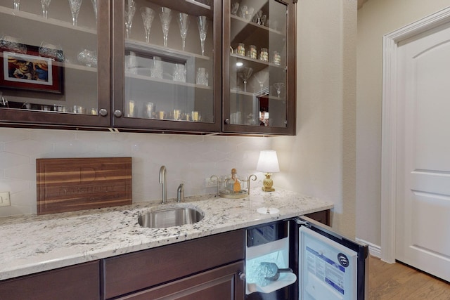 bar featuring decorative backsplash, dark brown cabinets, and sink